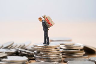 © Dilok - stock.adobe.com Foto: Figur mit Schuldensack auf dem Rücken